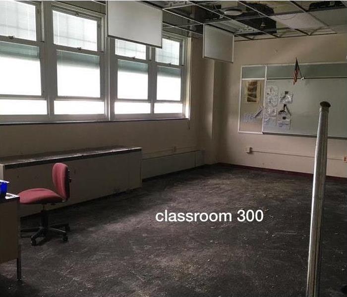 A classroom with wet carpet and hanging ceiling tiles