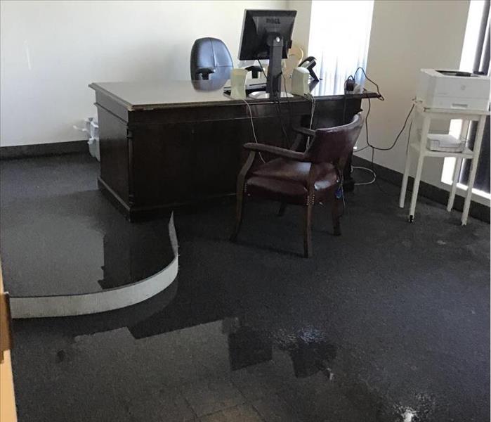 Standing water on the carpet of an office with a desk