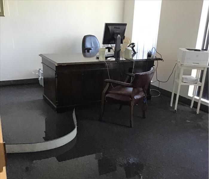 Standing water on the carpet of an office with a desk